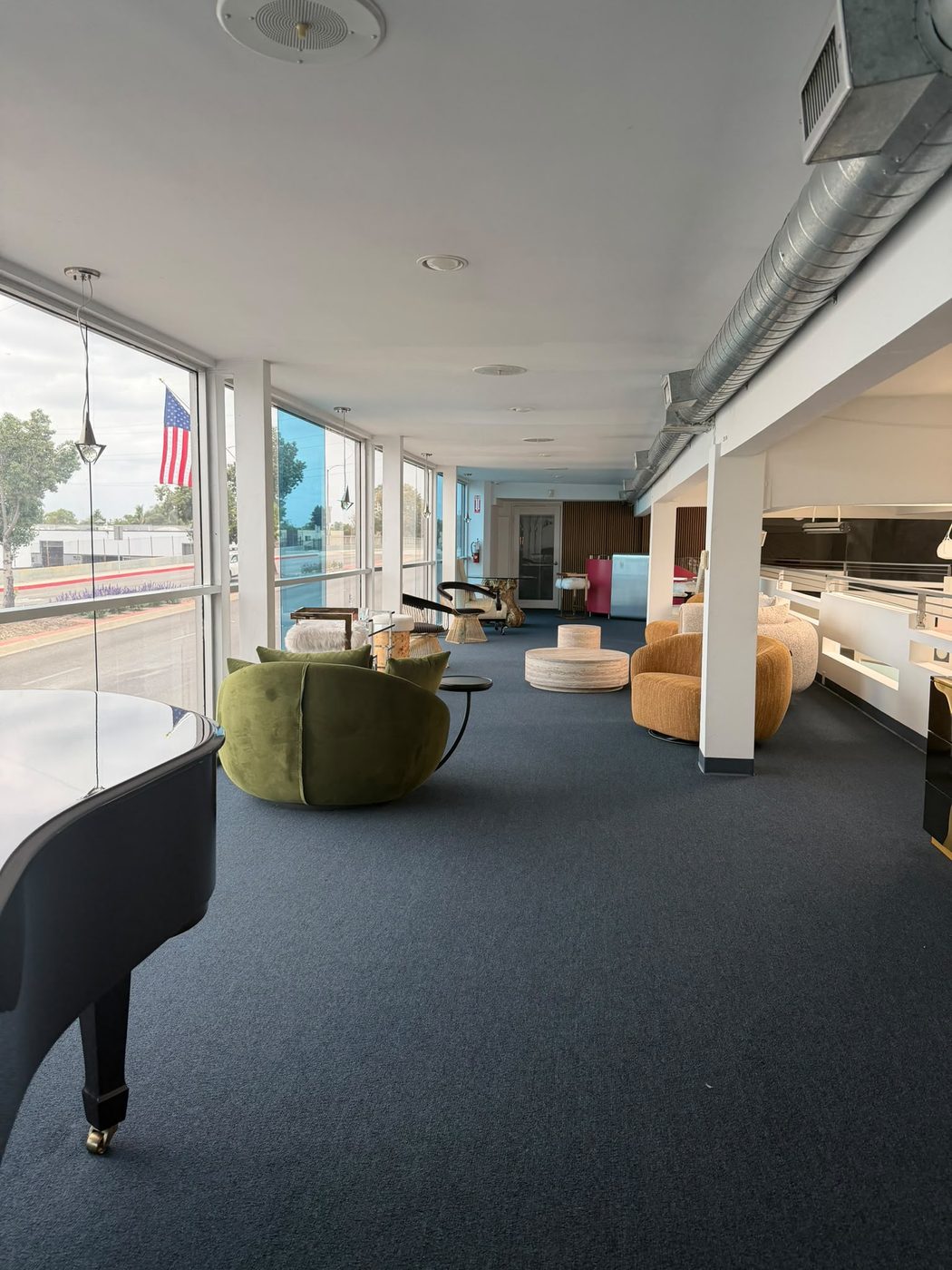 Lounge con piano de cola y ventanales hacia Florence Avenue